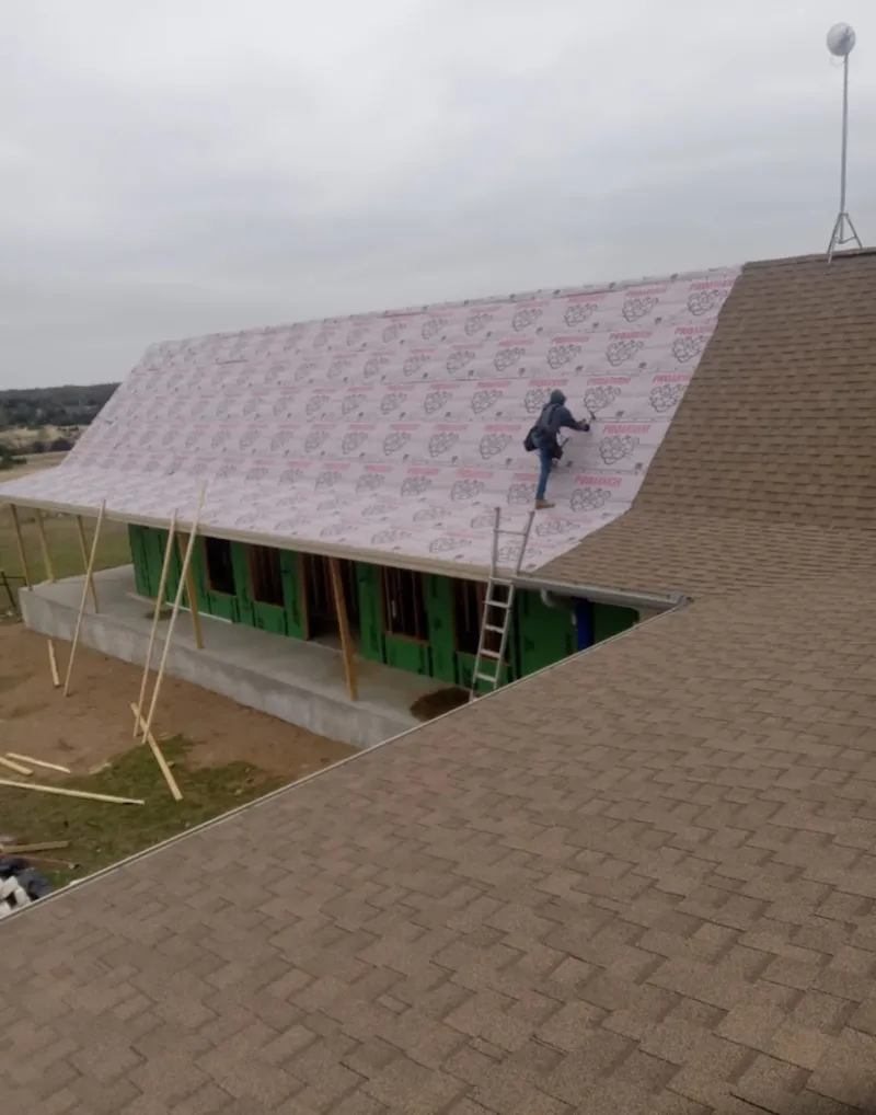 Worker preparing underlayment for a metal roof installation in Winslow